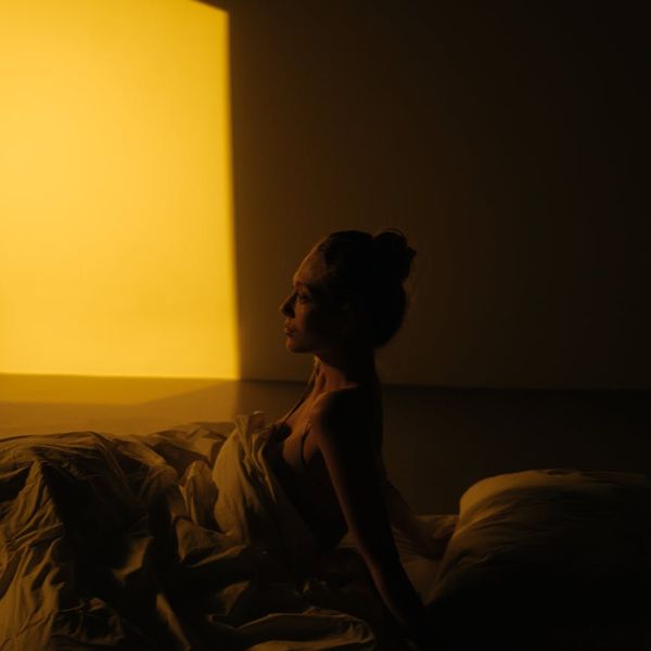 Person meditating peacefully in a minimalist setting with soft lighting.